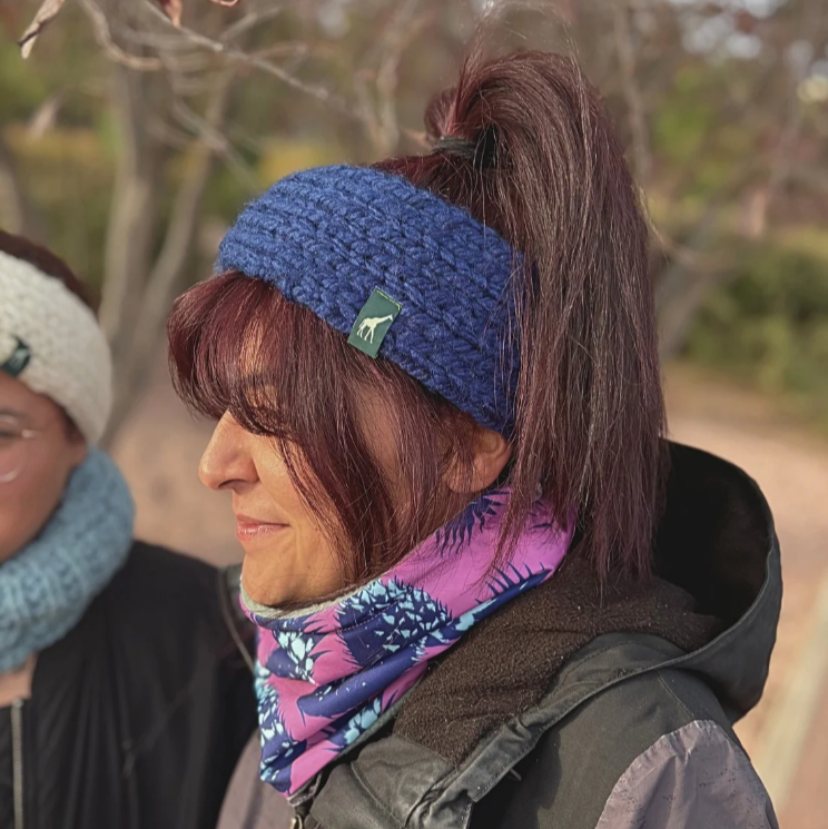 Person wearing a blue knitted headband with a logo outdoors